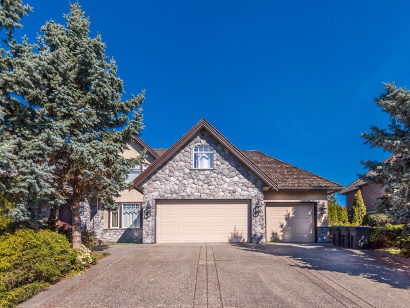 Beautiful exterior of newly built luxury home. Yard with green grass and walkway lead to ornately designed covered porch and front entrance.