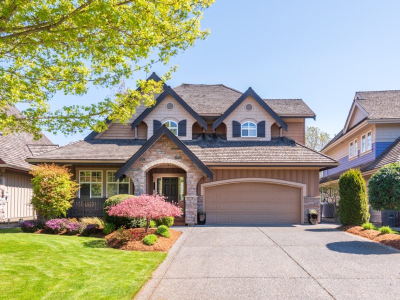 Beautiful exterior of newly built luxury home. Yard with green grass and walkway lead to front entrance.