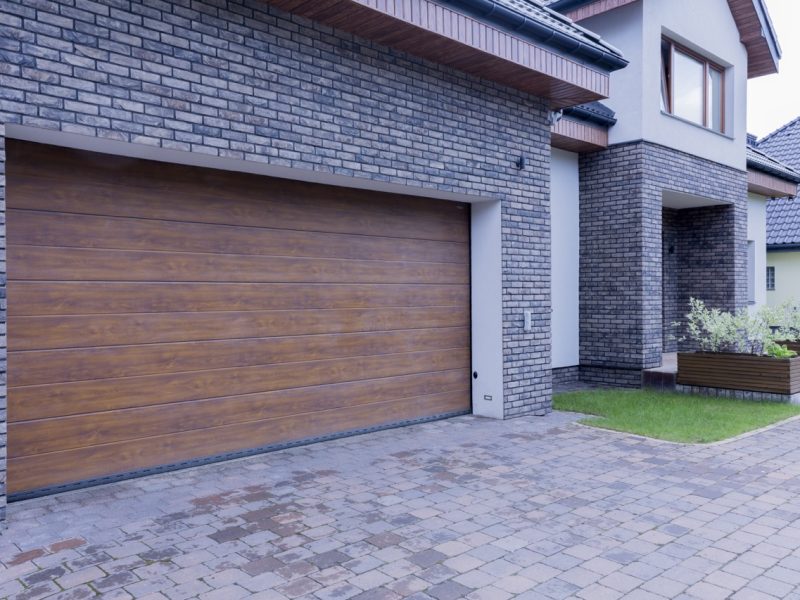 View of wooden garage door and main entrance of detached house